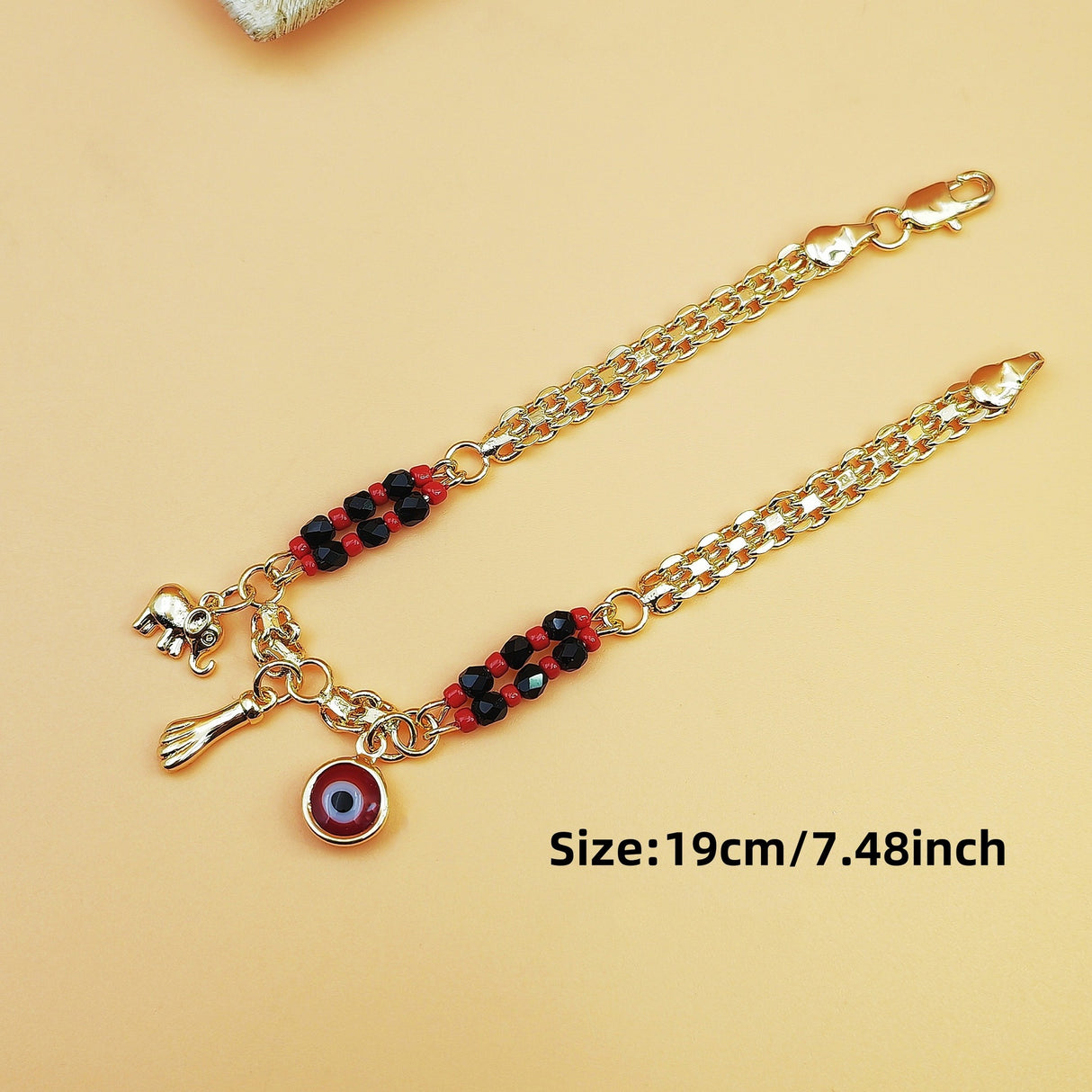 Gold-Tone Chain Bracelet with Red and Black Beads, Elephant Charm, Feather Pendant, and Round Stone Accent – 19 cm Length