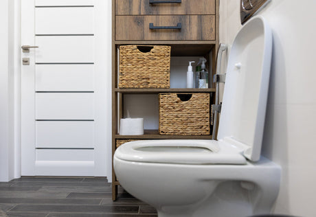 “Stylish bathroom with decorative elements around the toilet, including wall art, shelving, and plants for a modern look.”