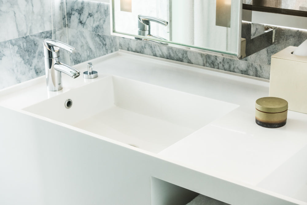 “Person aligning a new bathroom vanity against the wall, connecting plumbing and securing the unit to the floor and wall studs.”