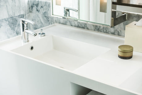 “Person aligning a new bathroom vanity against the wall, connecting plumbing and securing the unit to the floor and wall studs.”