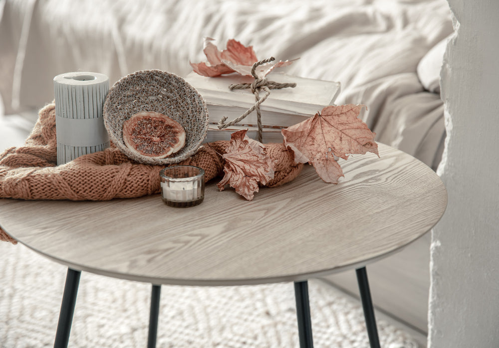 “Well-styled bedside table featuring a table lamp, stacked books, a small plant, and decorative accents in a cozy bedroom.”