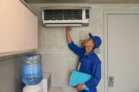 “Person sitting near an air conditioner holding a tissue, illustrating potential health effects like dry throat or sinus irritation from prolonged AC use.”