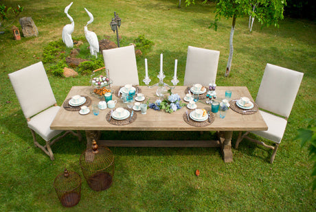 “Outdoor table decorated with a centerpiece of fresh flowers, tableware, and candles, styled for an inviting al fresco dining setup.”