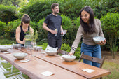 “Person constructing a wooden outdoor table using pre-cut timber, drill, and screws in a backyard DIY project.”