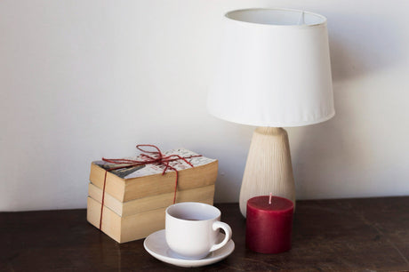 “Bedside table with must-have accessories including a lamp, alarm clock, books, glasses, and a water carafe.”
