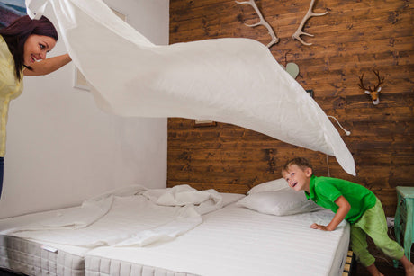 "Close-up of a hand smoothing a plush mattress topper on a neatly made bed, highlighting added comfort and support."