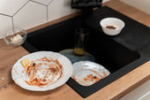 “Person pouring baking soda and vinegar into a kitchen sink drain to naturally remove buildup and eliminate odors.”