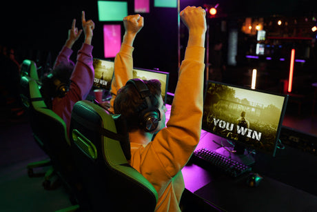 "Two high-performance gaming chairs side by side—one ergonomic with lumbar support, the other sleek and minimalist—set up in a gaming room with RGB lighting."
