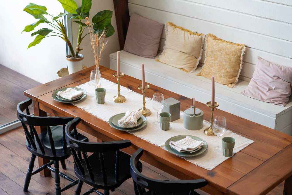 “Dining table styled with a central floral arrangement, candles, and layered place settings for a warm, welcoming atmosphere.”