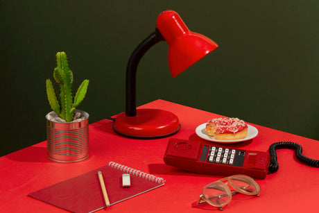 “Neatly styled desk with a table lamp, stationery holder, small plant, and framed art, creating a functional and inspiring workspace.”