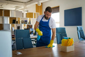 “Person cleaning an office chair with a microfiber cloth and mild cleaner, wiping down the seat and armrests to remove dust and stains.”