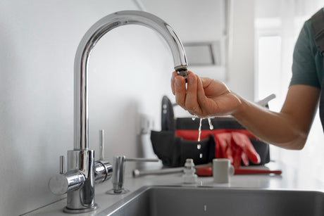 “Person replacing a worn tap washer inside a faucet to stop leaking, using a spanner and screwdriver.”