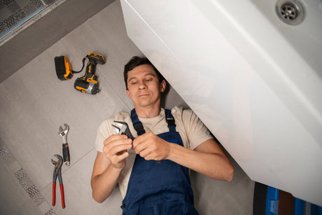 “Homeowner installing a freestanding bathtub, aligning the plumbing and securing the base in a modern bathroom.”