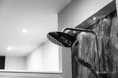 “Person installing a new shower head onto a wall-mounted shower arm using a wrench and plumber’s tape for a secure fit.”