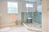 “Frameless glass shower screen being installed by aligning the panel with wall brackets and securing it using a level and drill.”