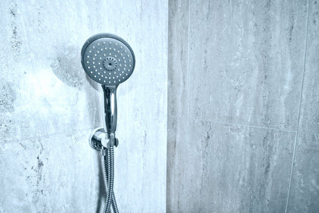 “Person unscrewing an old shower head and installing a new chrome fixture using a wrench and plumber’s tape.”