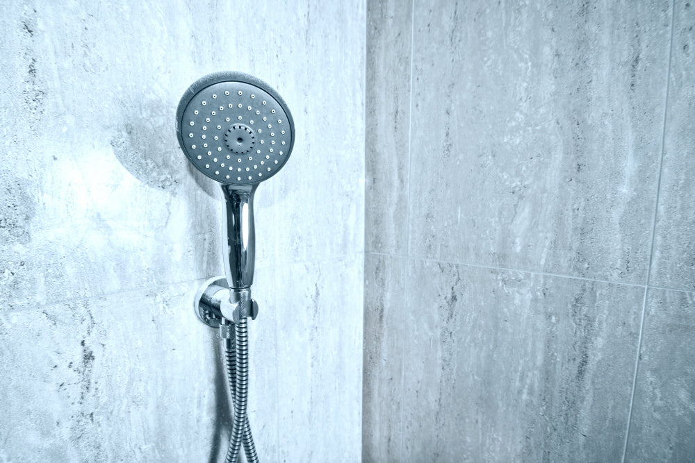 “Person unscrewing an old shower head and installing a new chrome fixture using a wrench and plumber’s tape.”