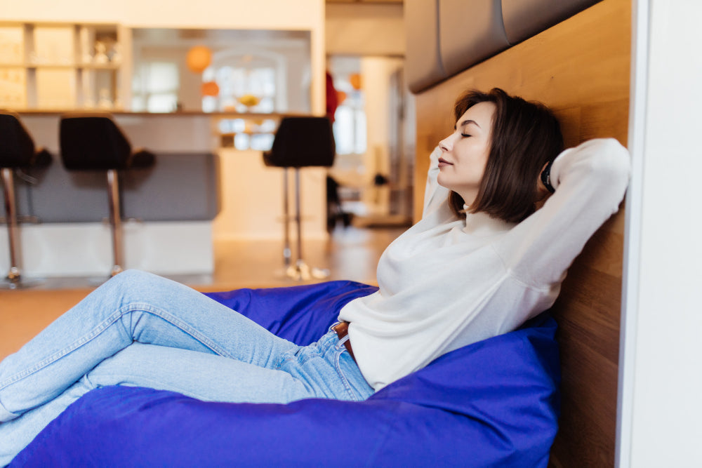  "Person reclining peacefully in a cozy chair with dim lighting, practicing relaxation techniques to improve sleep quality."