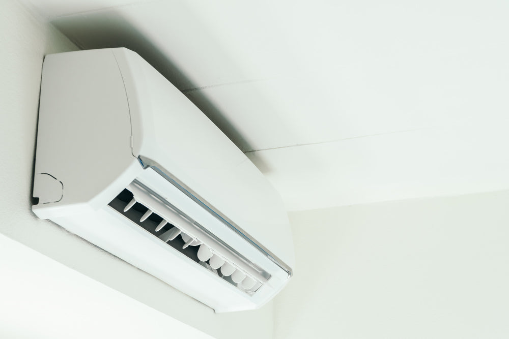 “Diagram of an air conditioner showing how warm air is drawn in, cooled by refrigerant coils, and blown back out to lower indoor temperature.”