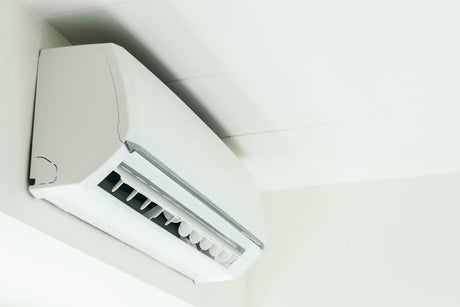 “Diagram of an air conditioner showing how warm air is drawn in, cooled by refrigerant coils, and blown back out to lower indoor temperature.”