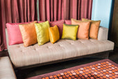“Neutral-toned sofa styled with layered cushions in varying sizes, textures, and colors, arranged symmetrically for a polished and inviting look.”