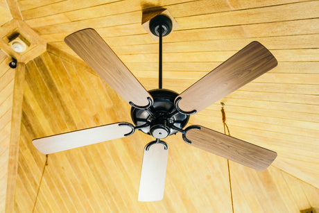 “Electrician installing a ceiling fan in a modern room, highlighting tools and wiring involved in a typical ceiling fan installation.”