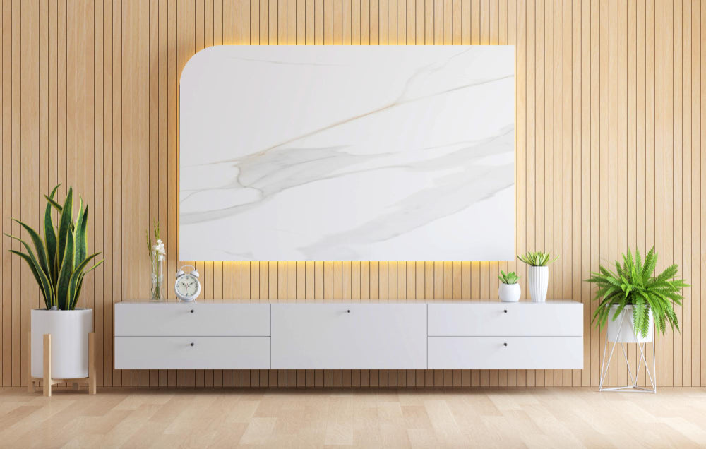 “Modern TV unit styled with a mounted TV, floating shelves, framed art, plants, and decorative objects for a balanced and stylish look.”