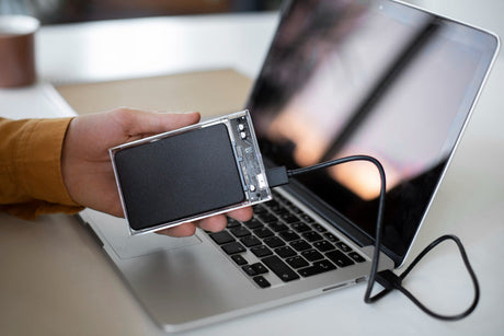 "User adjusting laptop settings and cleaning vents, illustrating tips for improving battery life and system performance."