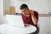 "Person working at a desk using a laptop stand, maintaining upright posture and eye-level screen position to reduce neck and back strain."