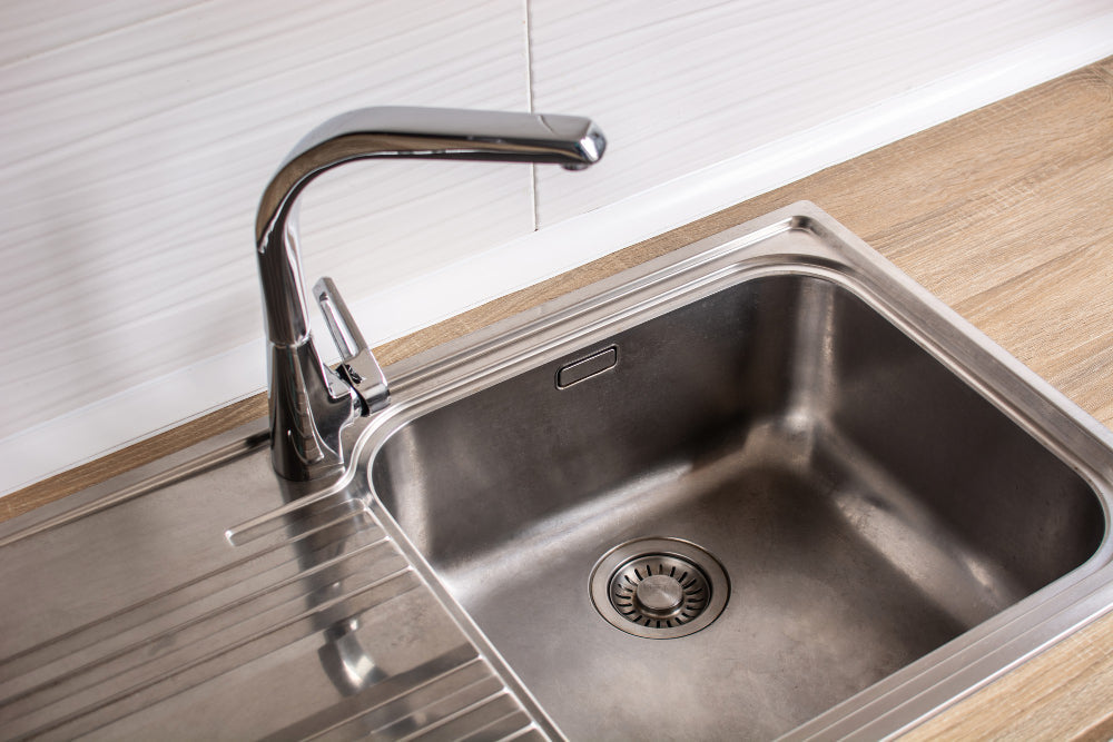 "Display of various modern sink materials including stainless steel, ceramic, glass, and stone, showcasing diverse textures and finishes in a showroom setting."