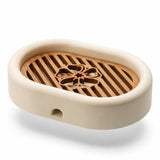 3D-printed oval soap dish with drain rack, white and wood-look.
