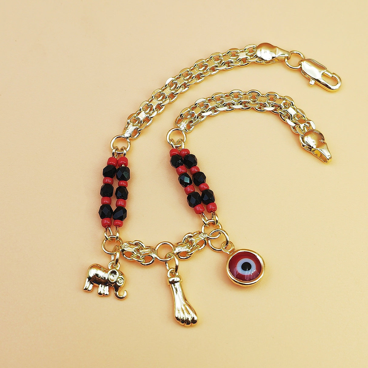 Gold-Tone Chain Bracelet with Red and Black Beads, Elephant Charm, Feather Pendant, and Round Stone Accent – 19 cm Length