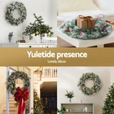 Jingle Jollys 60cm Illuminated Snow-Frosted Christmas Wreath with Red Berry Accents - 45-Degree Angle